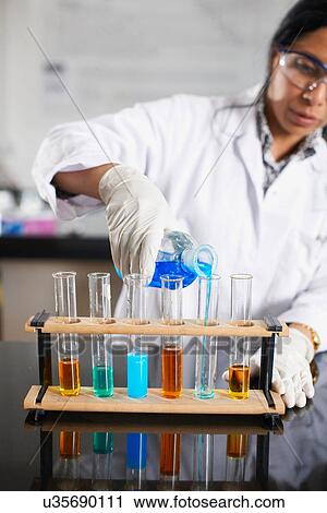 Chemistry teacher pouring chemicals into test tubes View Large Photo Image Stock Image - Chemistry teacher pouring chemicals into test tubes. Fotosearch
