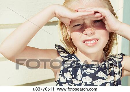 Stock Image - Child covering her eyes from sun glare. Fotosearch