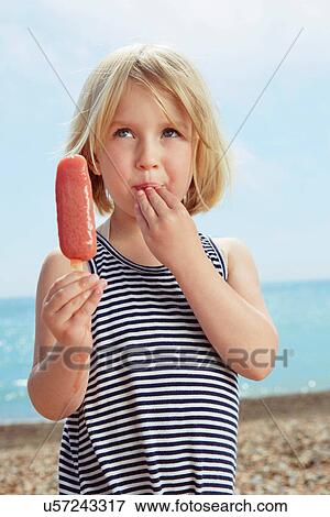 Stock Photo - Child with fingers on lip holding ice lolly. Fotosearch