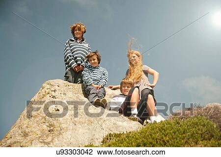 Stock Image - Children sitting on rocks. Fotosearch