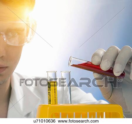 Stock Photograph - Close up of scientist pouring liquid from test tube. Fotosearch
