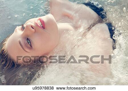 Stock Photo - Close up portrait of young woman lying back in sea. Fotosearch