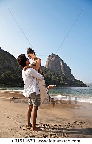 Couple hugging on beach, man lifting woman, Rio de Janeiro, Brazil View Large Photo Image Stock Image - Couple hugging on beach, man lifting woman, Rio de Janeiro, Brazil. Fotosearch
