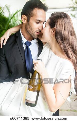 Stock Photography - Couple hugging, woman holding wine bottle. Fotosearch