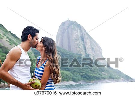 Stock Photograph - Couple kissing on beach with Sugarloaf Mountain, Rio de Janeiro, Brazil. Fotosearch