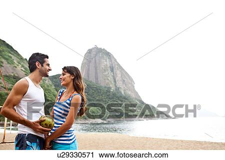 Stock Image - Couple on beach with Sugarloaf Mountain, Rio de Janeiro, Brazil. Fotosearch