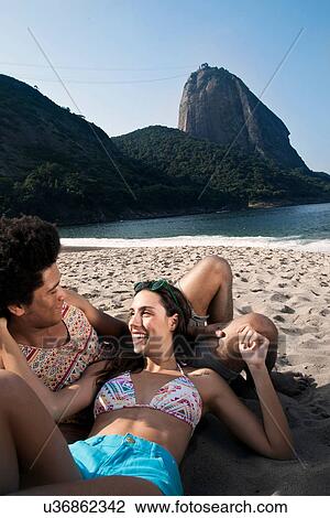 Stock Image - Couple relaxing on beach, Rio de Janeiro, Brazil. Fotosearch