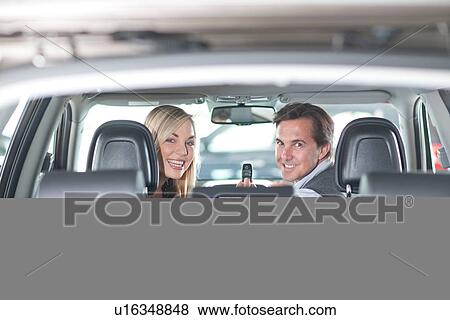 Stock Photo - Couple sitting in new car in showroom. Fotosearch