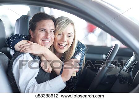 Couple sitting in new car with key in showroom View Large Photo Image Stock Image - Couple sitting in new car with key in showroom. Fotosearch