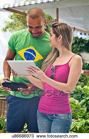 Couple using digital tablet in market View Large Photo Image Stock Image - Couple using digital tablet in market. Fotosearch