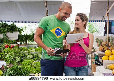 Couple using digital tablet in market View Large Photo Image Stock Photograph - Couple using digital tablet in market. Fotosearch