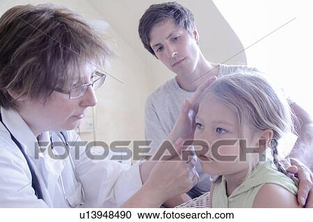 Stock Image - Doctor examining girl, father watching. Fotosearch