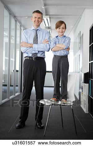 Stock Photo - Father and son in office, boy standing on chair. Fotosearch