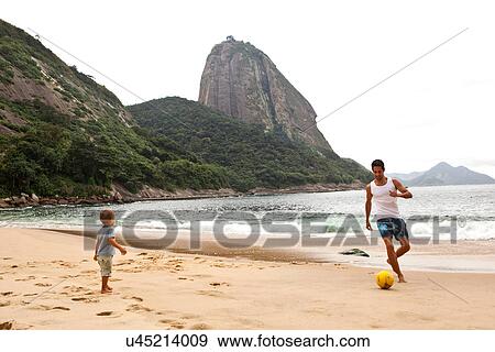 Father and son playing football on beach, Rio de Janeiro, Brazil View Large Photo Image Stock Photo - Father and son playing football on beach, Rio de Janeiro, Brazil. Fotosearch