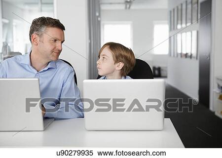 Father and son using laptops, face to face View Large Photo Image Stock Photography - Father and son using laptops, face to face. Fotosearch