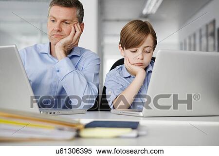 Stock Photography - Father and son using laptops looking bored. Fotosearch