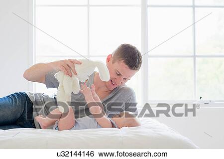 Father holding soft toy above baby View Large Photo Image Stock Photograph - Father holding soft toy above baby. Fotosearch