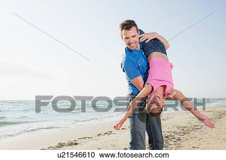 Stock Image - Father playing with daughter, tipping upside down. Fotosearch