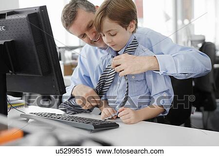Stock Photography - Father putting tie on son at desk. Fotosearch