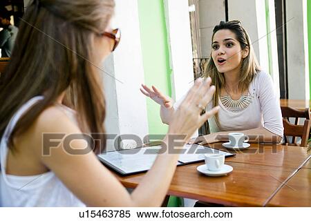Female friends having conversation outside cafe View Large Photo Image Stock Photography - Female friends having conversation outside cafe. Fotosearch