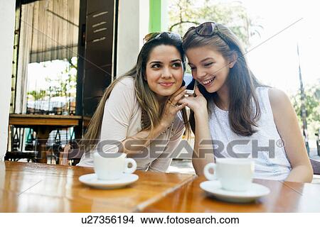 Female friends listening to cellphone together View Large Photo Image Picture - Female friends listening to cellphone together. Fotosearch