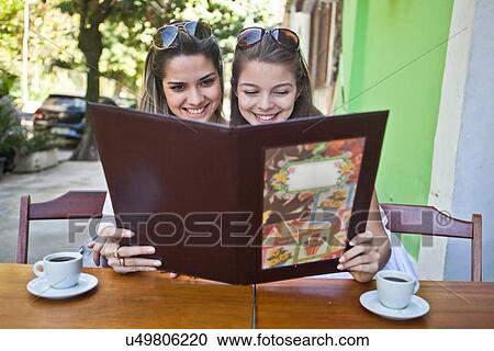 Female friends looking at cafe menu together View Large Photo Image Stock Image - Female friends looking at cafe menu together. Fotosearch