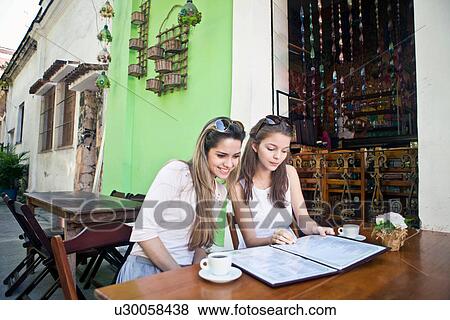 Stock Photo - Female friends looking at cafe menu. Fotosearch