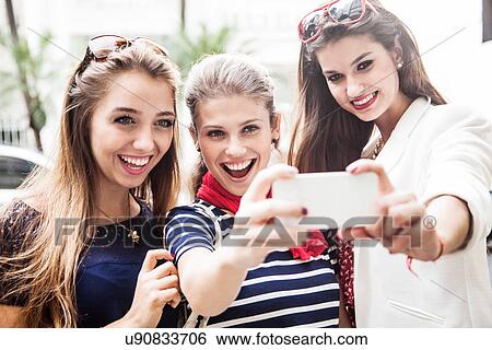 Female friends taking photograph of themselves View Large Photo Image Stock Photograph - Female friends taking photograph of themselves. Fotosearch