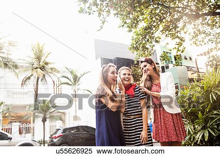 Stock Photography - Female friends using cellphone. Fotosearch