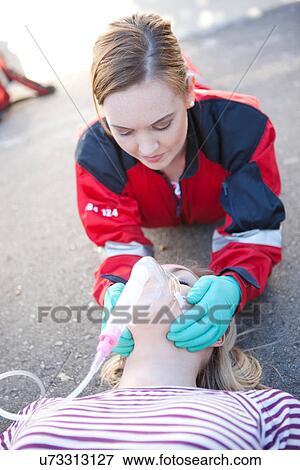 Stock Photo - Female paramedic tending patient on road. Fotosearch