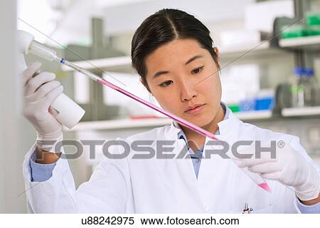 Stock Photography - Female scientist pipetting liquid for reaction mixture. Fotosearch