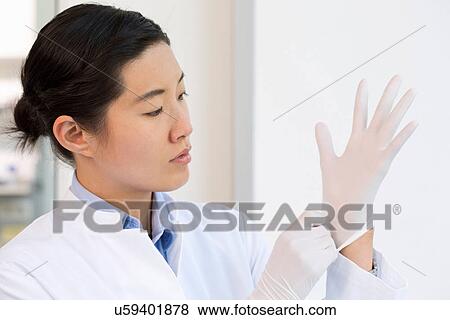 Stock Photo - Female scientist putting on gloves. Fotosearch