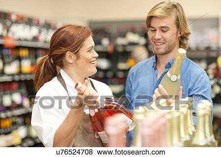 Female shop assistant advising customer on wine View Large Photo Image Stock Photo - Female shop assistant advising customer on wine. Fotosearch