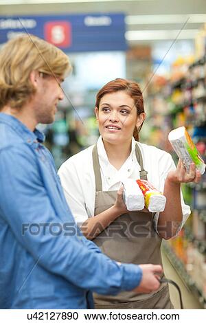 Stock Image - Female shop assistant advising male customer. Fotosearch