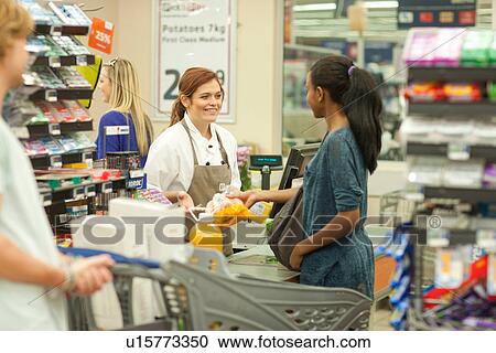 Female shop assistant at check-out View Large Photo Image Stock Image - Female shop assistant at check-out. Fotosearch