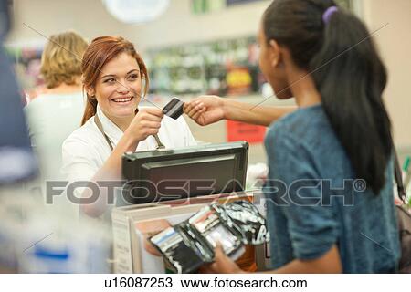 Female shop assistant receiving card from customer View Large Photo Image Stock Image - Female shop assistant receiving card from customer. Fotosearch