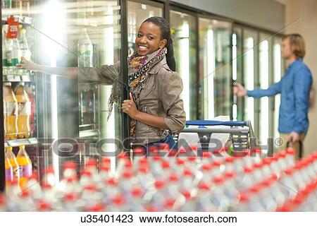 Female shopper reaching for soft drink from cooler View Large Photo Image Stock Image - Female shopper reaching for soft drink from cooler. Fotosearch