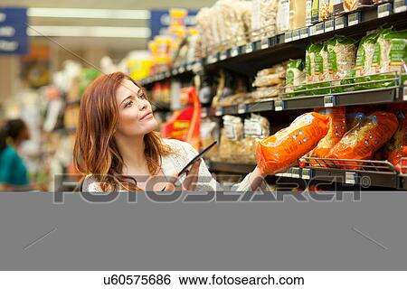 Female shopper with digital tablet in supermarket View Large Photo Image Stock Photograph - Female shopper with digital tablet in supermarket. Fotosearch