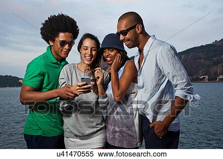 Four friends looking at cell phone View Large Photo Image Stock Photography - Four friends looking at cell phone. Fotosearch