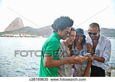 Four friends looking at smartphone, Rio de Janeiro, Brazil View Large Photo Image Stock Photography - Four friends looking at smartphone, Rio de Janeiro, Brazil. Fotosearch
