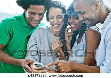 Four friends looking at smartphone View Large Photo Image Stock Image - Four friends looking at smartphone. Fotosearch