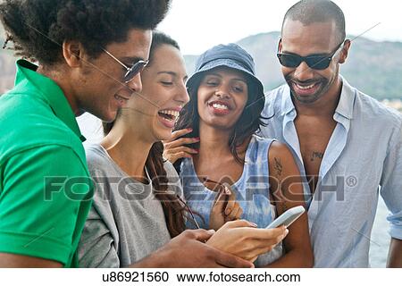 Four friends looking at smartphone View Large Photo Image Stock Image - Four friends looking at smartphone. Fotosearch