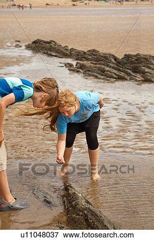 Friends looking in rock pool View Large Photo Image Stock Photo - Friends looking in rock pool. Fotosearch
