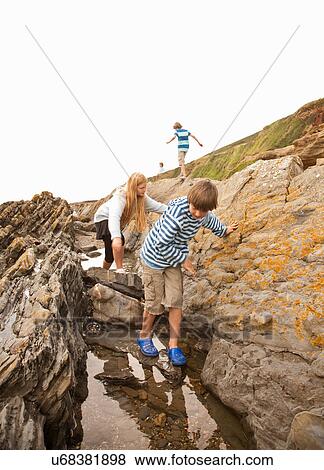 Stock Photo - Friends looking in rock pool. Fotosearch