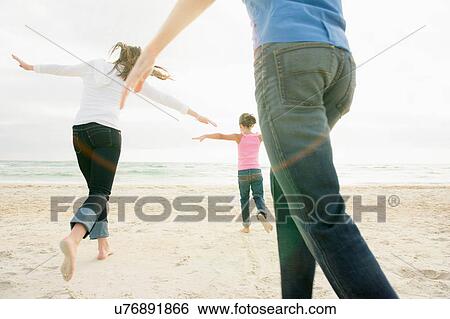 Stock Photograph - Girl and parents running with arms open. Fotosearch