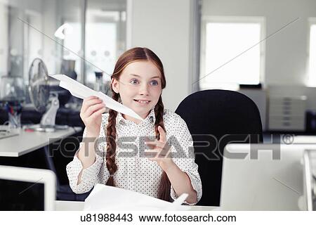 Girl holding paper airplane in office View Large Photo Image Stock Image - Girl holding paper airplane in office. Fotosearch