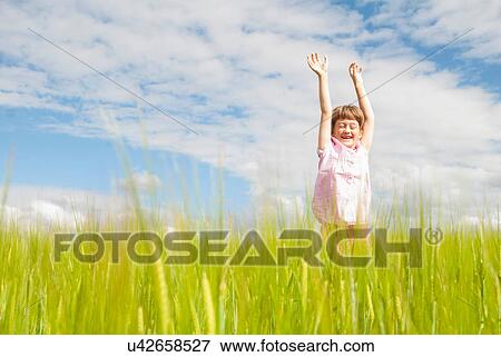 Girl in field with arms raised View Large Photo Image Stock Photo - Girl in field with arms raised. Fotosearch