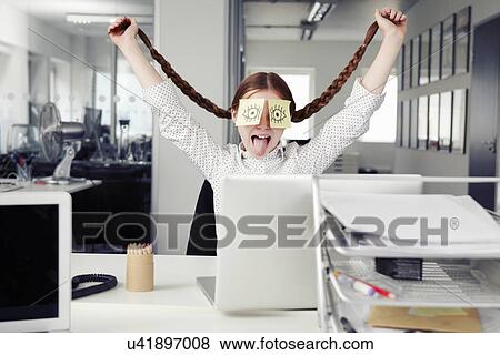 Stock Photo - Girl in office with adhesive notes covering eyes holding plaits. Fotosearch