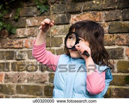 Stock Image - Girl looking at worm with magnifying glass. Fotosearch