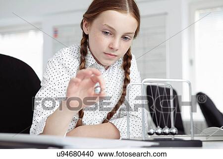 Girl playing with newton's cradle on desk View Large Photo Image Stock Image - Girl playing with newton's cradle on desk. Fotosearch